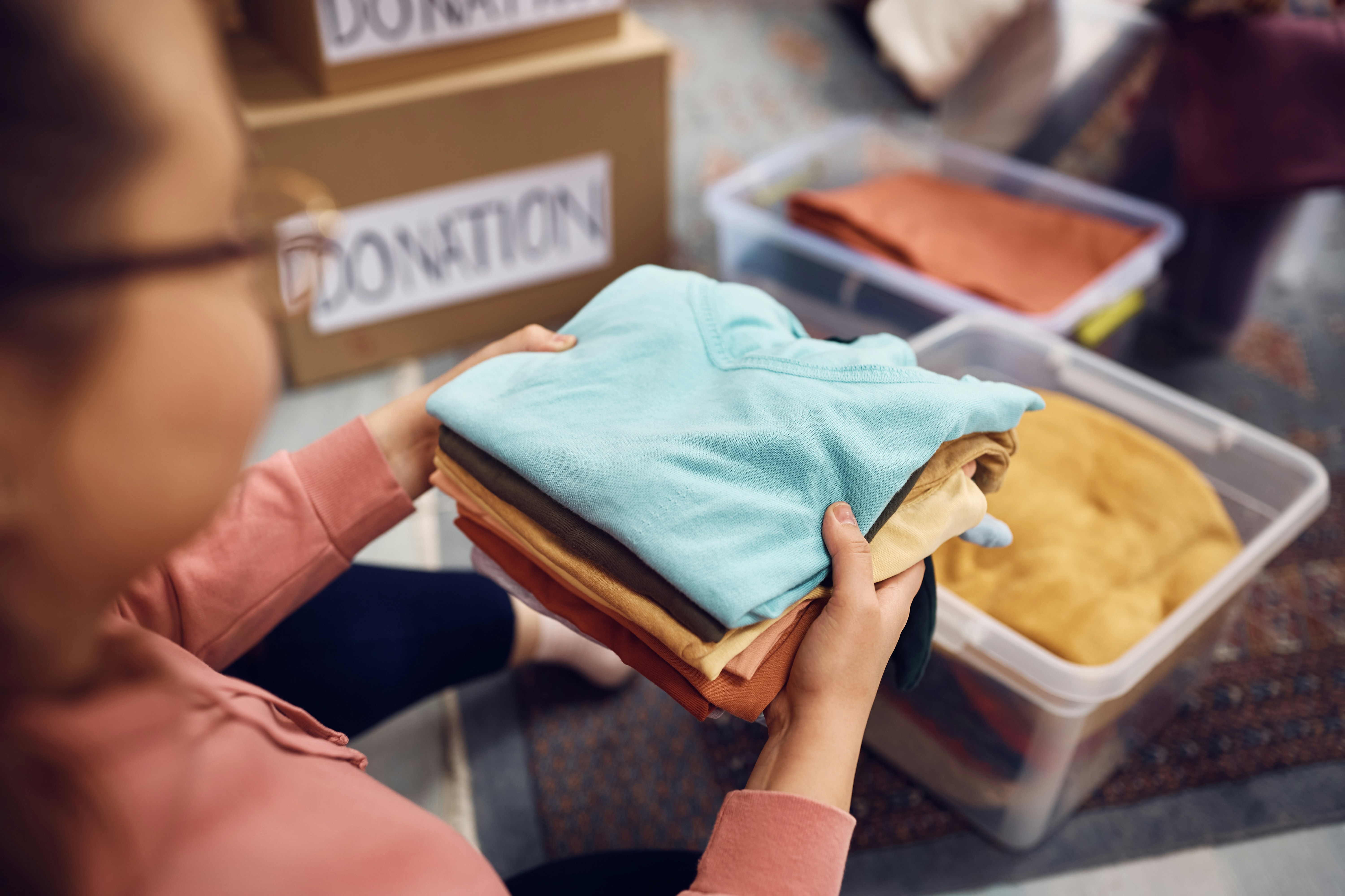 Volunteer sorting folded clothing into labelled donation boxes